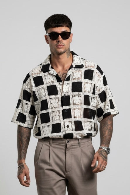 Modello indossa camicia GetOneStore-civitavecchia a maniche corte con motivo geometrico bianco e nero e pantaloni beige